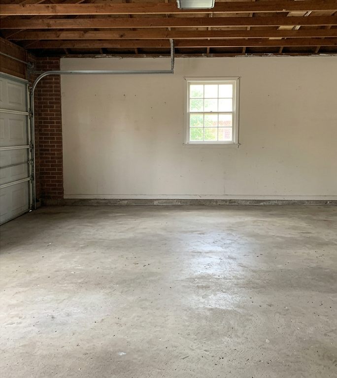 Two-car garage after cleanout: empty with a clean concrete floor and a window