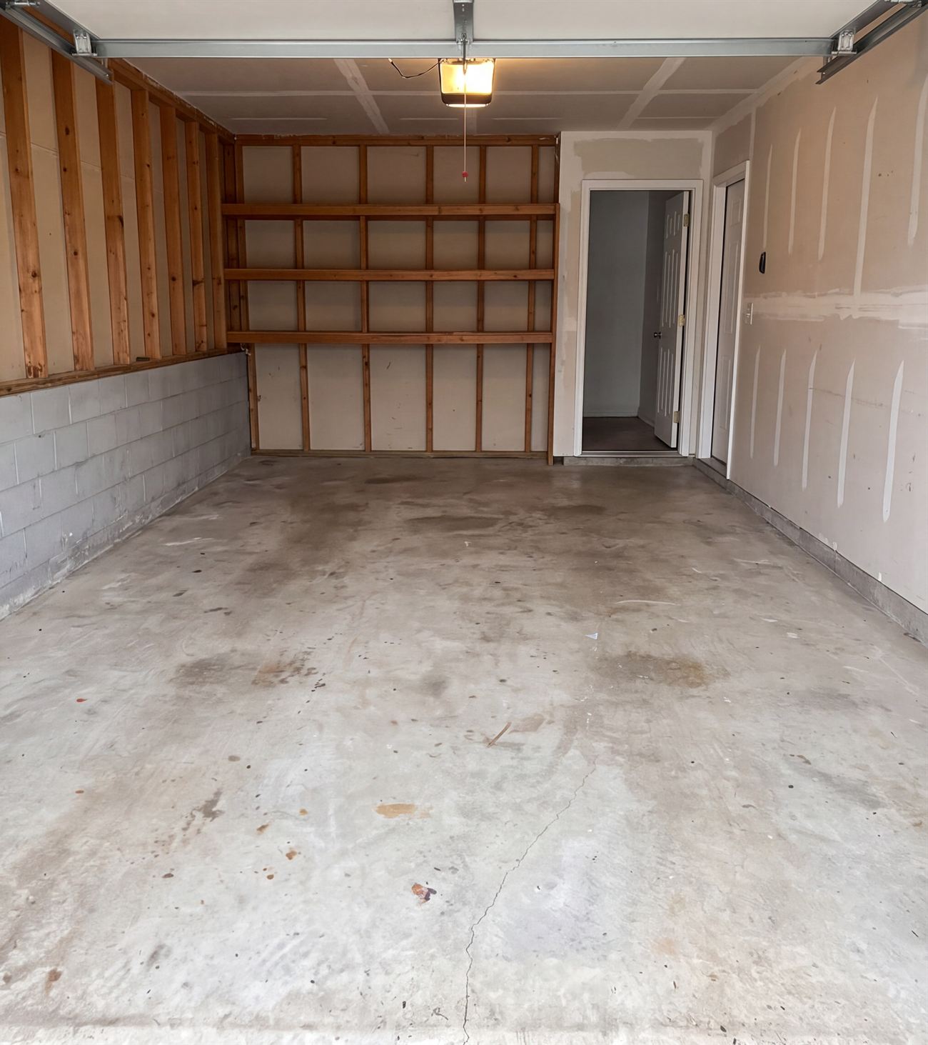 A cleared, swept garage with bare studs, shelving and a doorway